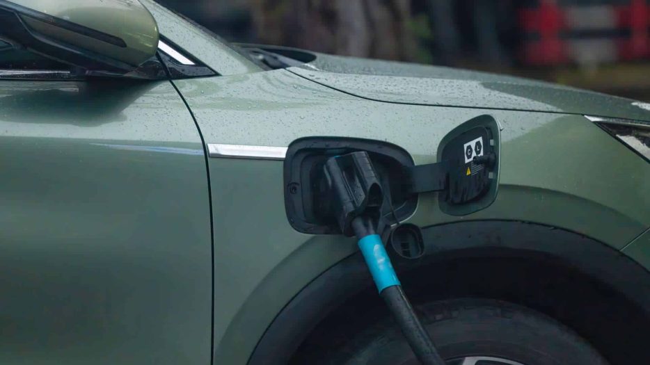 Une voiture électrique verte en pleine recharge sur une borne de recharge