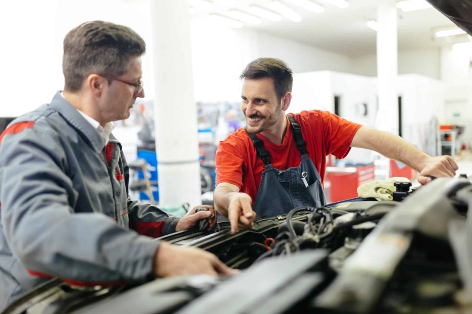 Car mechanics fixing car in garage - teamwork